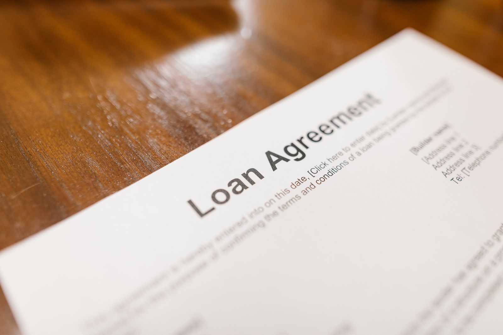 나무 탁자 위에 비스듬히 놓인 ‘Loan Agreement’ 제목의 영문 대출계약서 양식